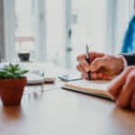 businessman writing in notebook at office desk 2026 03 24 23 50 16 utc