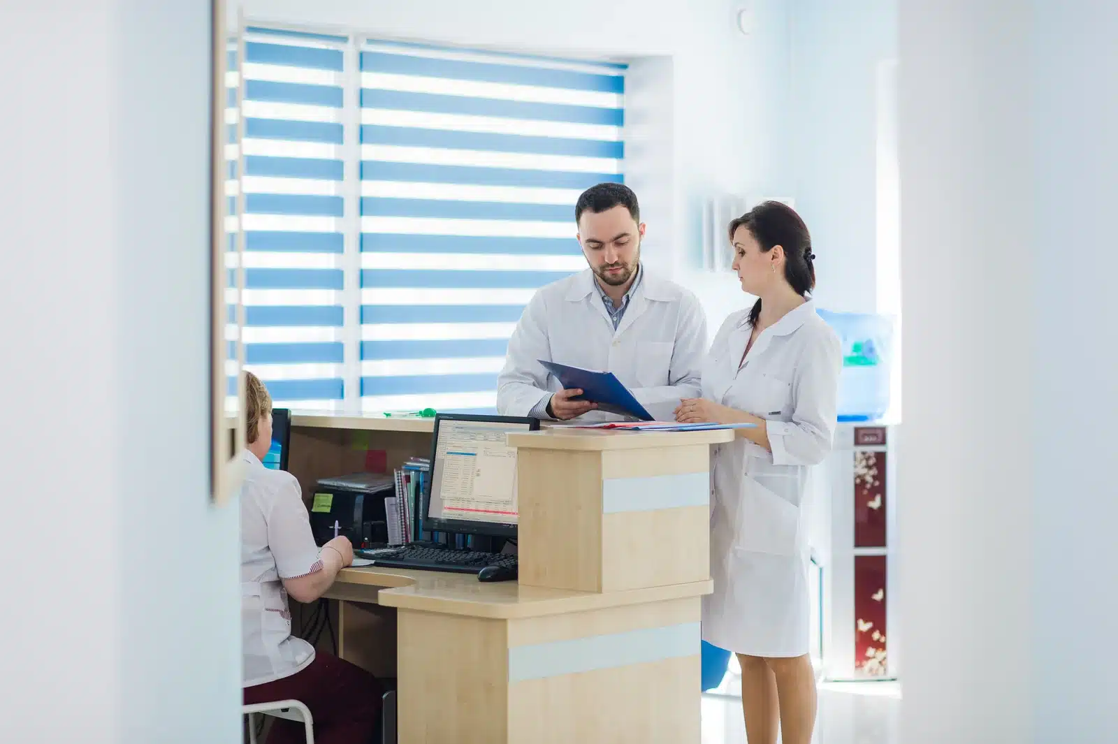 Front desk staff reviewing patient insurance paperwork at a behavioral health clinic reception